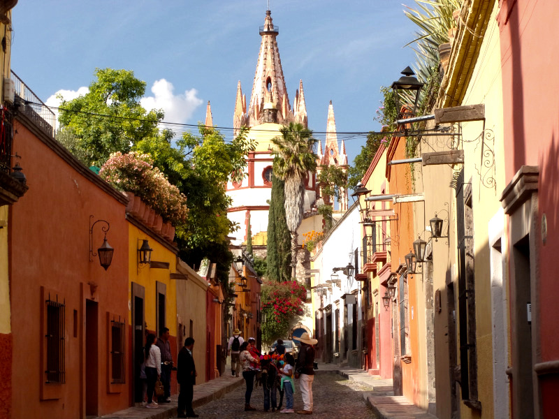 A man on the street with a donkey on a colorful colonial street in San Miguel De Allende one of the best cities in Mexico for digital nomads