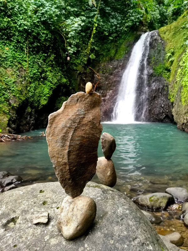 A pile of rocks in front of Seven Sisters Waterfall - one of the best waterfalls in Grenada