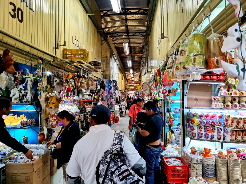 The inside of Sonora market with people walking through the isles selling miscellaneous things 