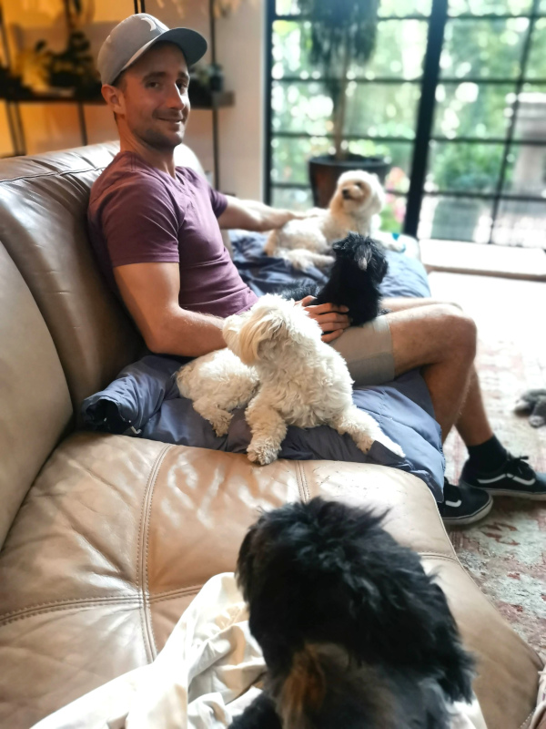 Allan sitting on a couch with four dogs while pet sitting in San Miguel de Allende