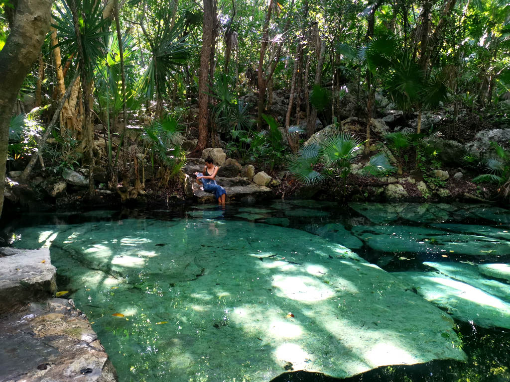 Sitting on the edge of the first pool at Cenote Azul surrounded by jungle near Playa Del Carmen
