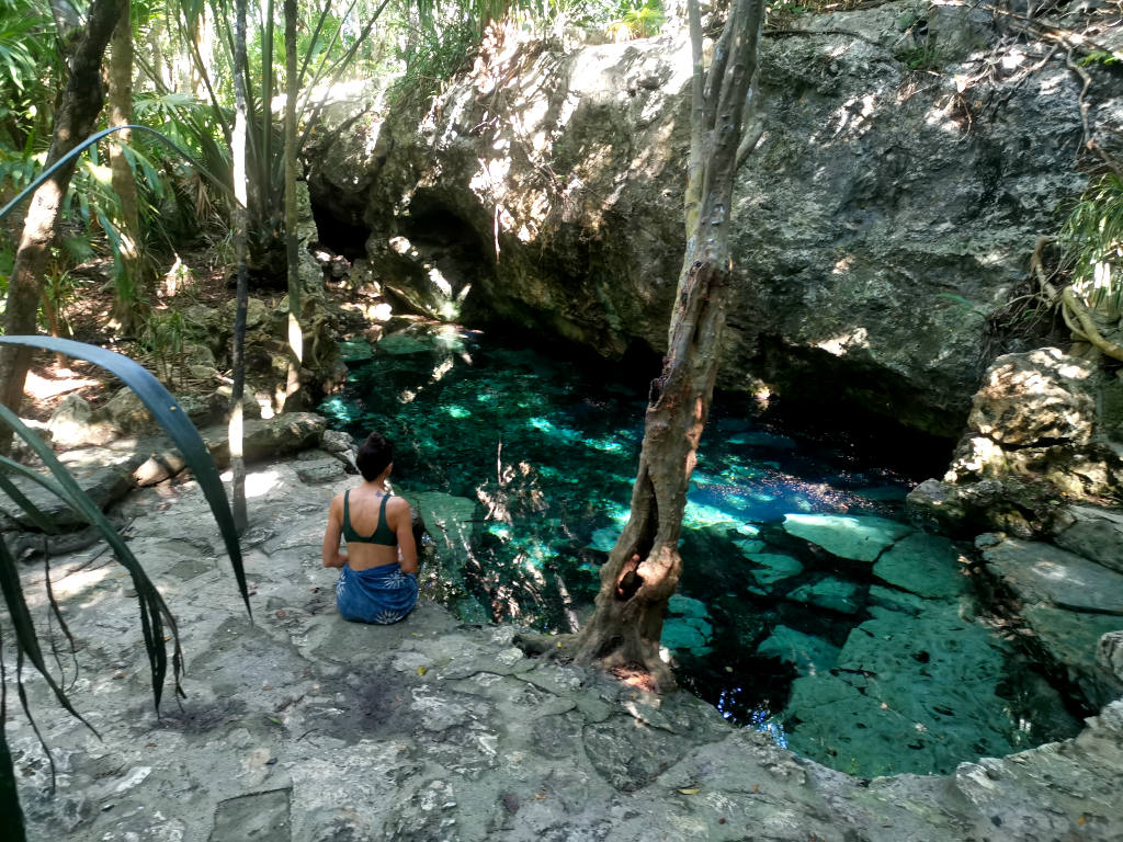 Katharina sitting on the edge of a pool at Cenote Azul - one of the best cenotes Playa del Carmen