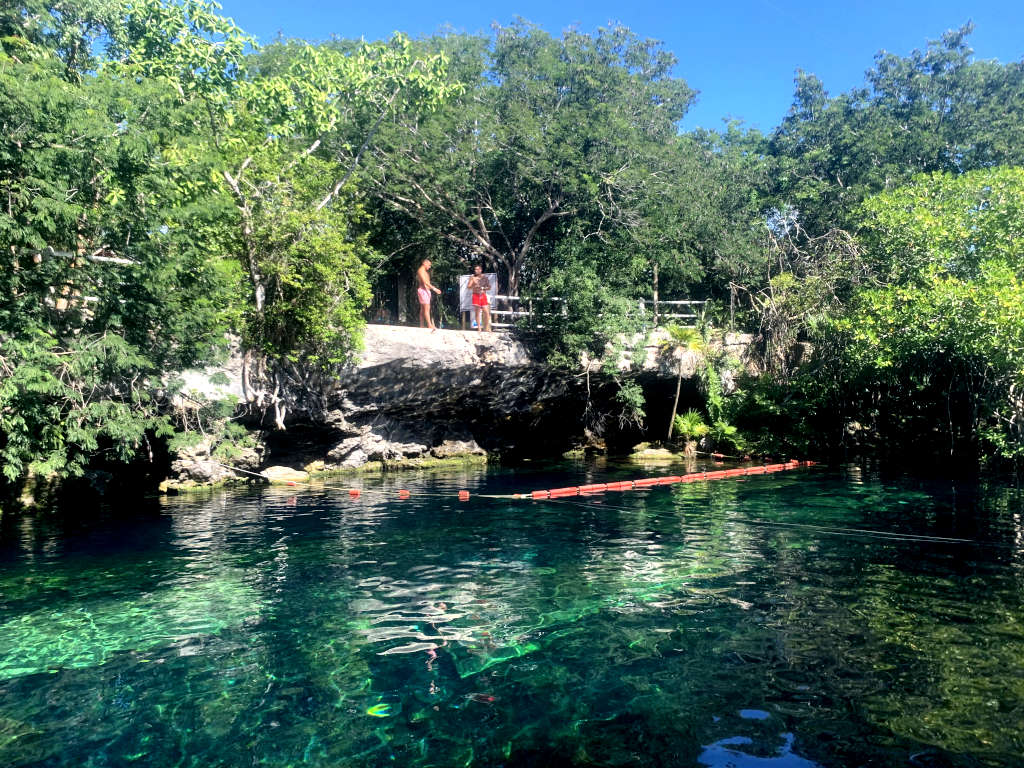 Two guys getting ready to jump of a ledge into Cenote Cristalino