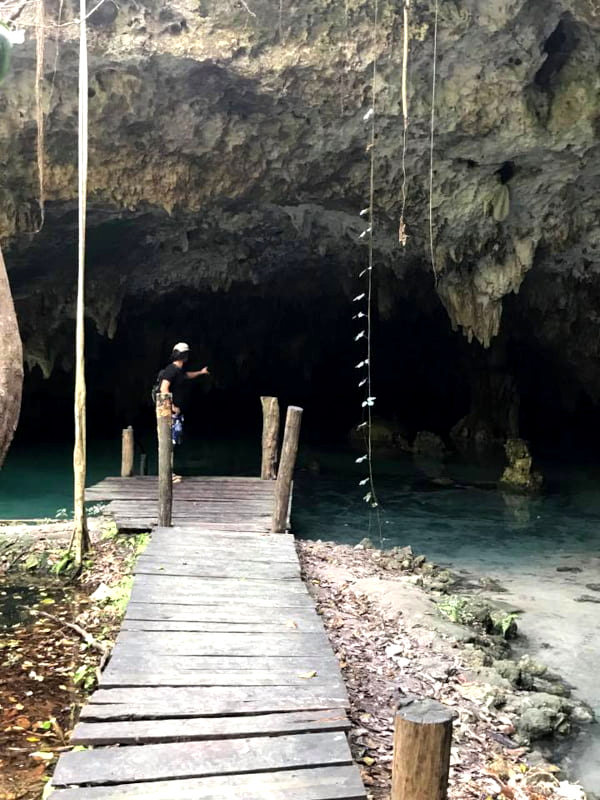 Standing on a wooden wharf at the entrance to Cenote Sac Actun