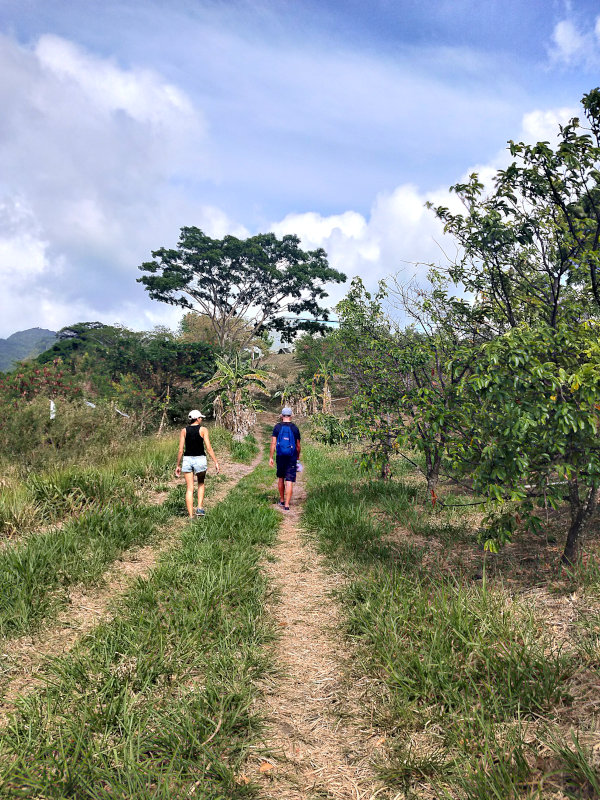 A man and a woman walking down a dirt path in the countryside in Grenada