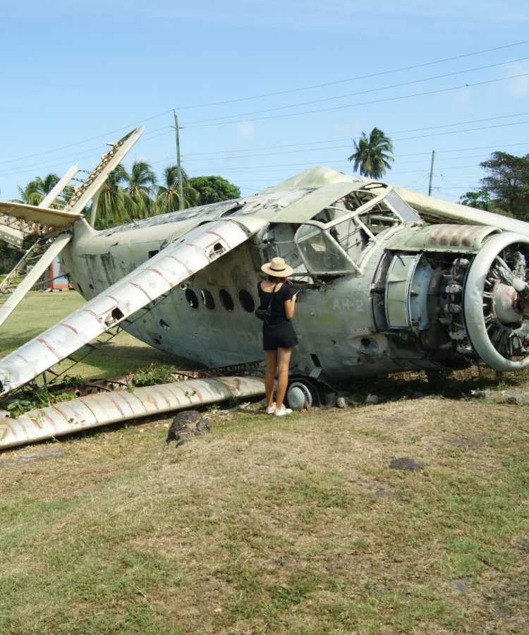 A woman looking inside an abandoned plane at pearls aiport in grenada