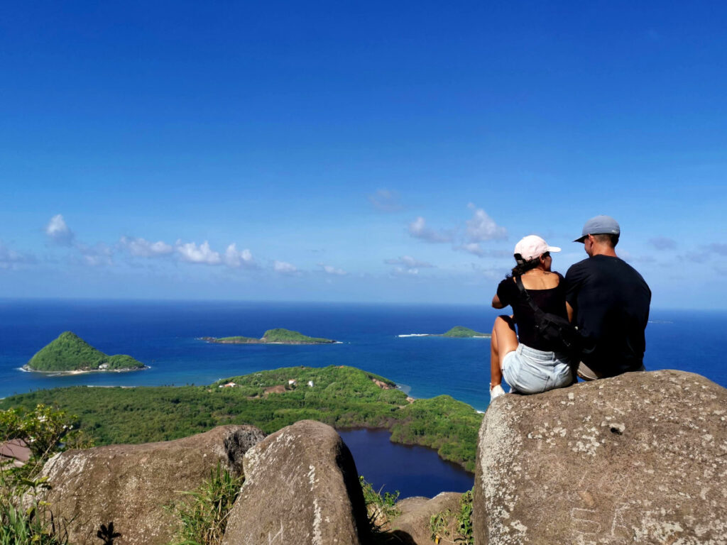 A couple sitting on a rock overlooking the ocean on Welcome Stone Grenada