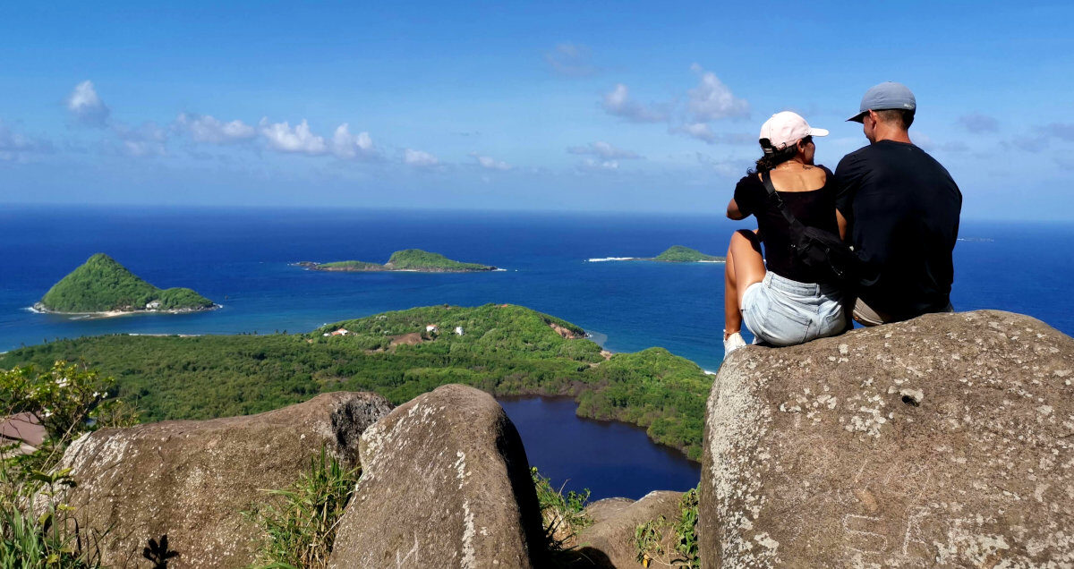 A couple sitting on a rock overlooking the ocean on Welcome Stone Grenada