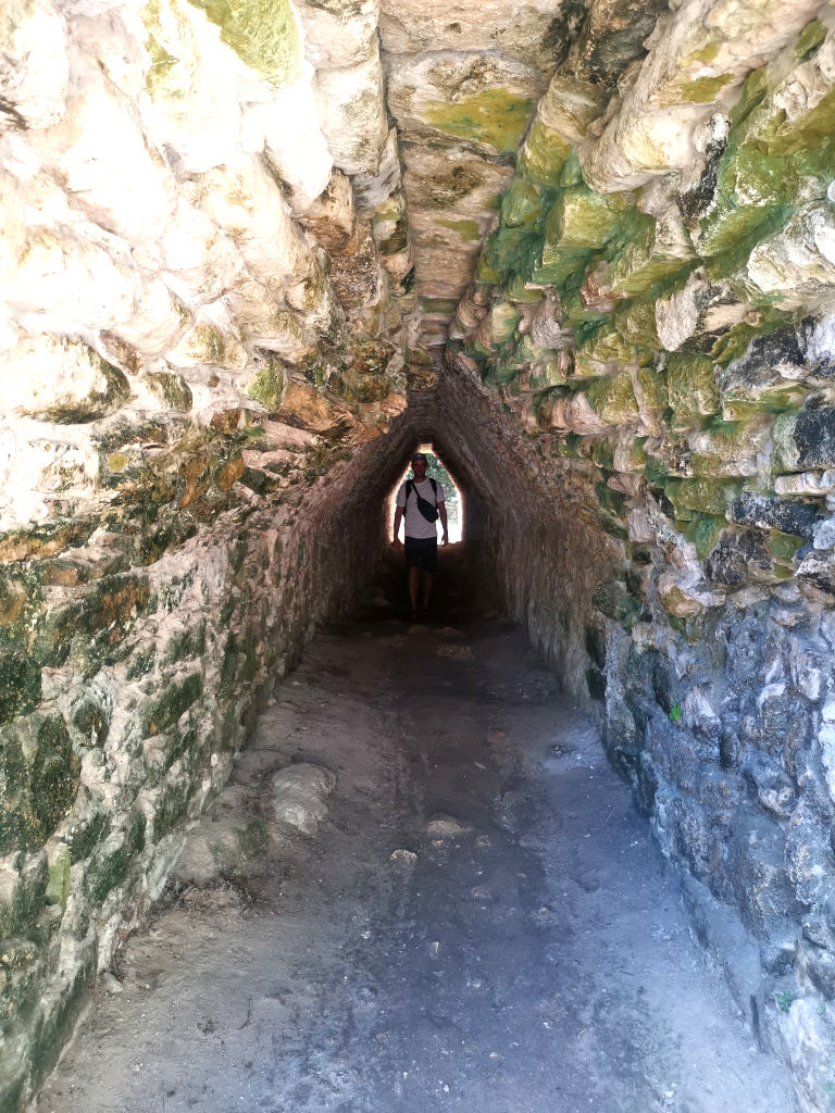 A man walking through a tunnel at some mayan ruins on the yucatan peninsula in Mexico