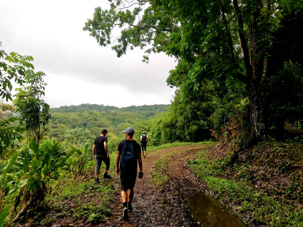 Three people hiking along a muddy road in Grenada
