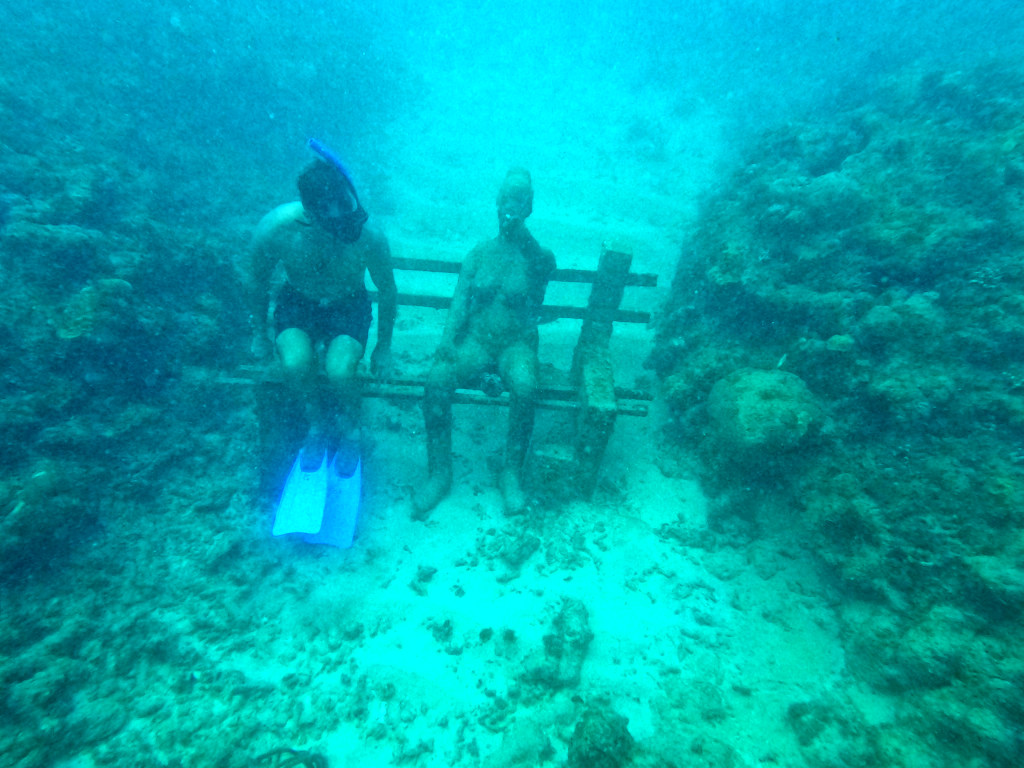 A man sitting on a bench at the Grenada Underwater Sculpture Park while snorkeling