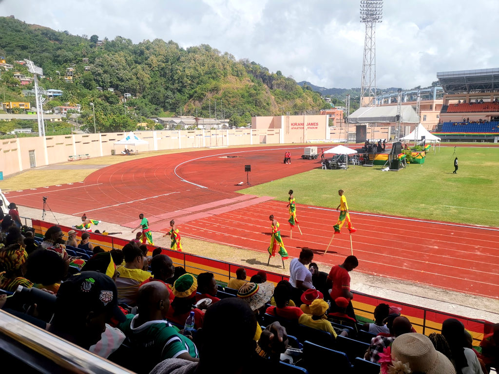 A group of people walking on stilts in a stadium in Grenada