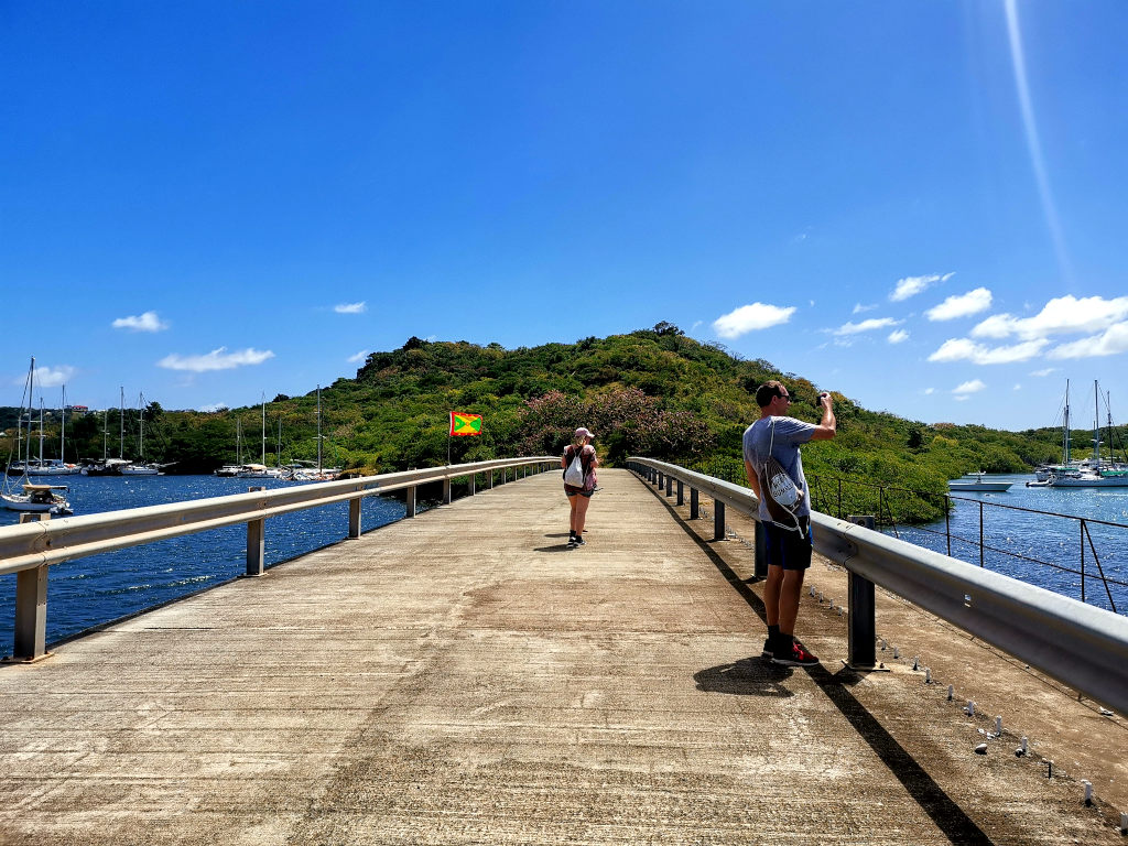 Two people walking over a bridge while hiking to Hog Island Grenada