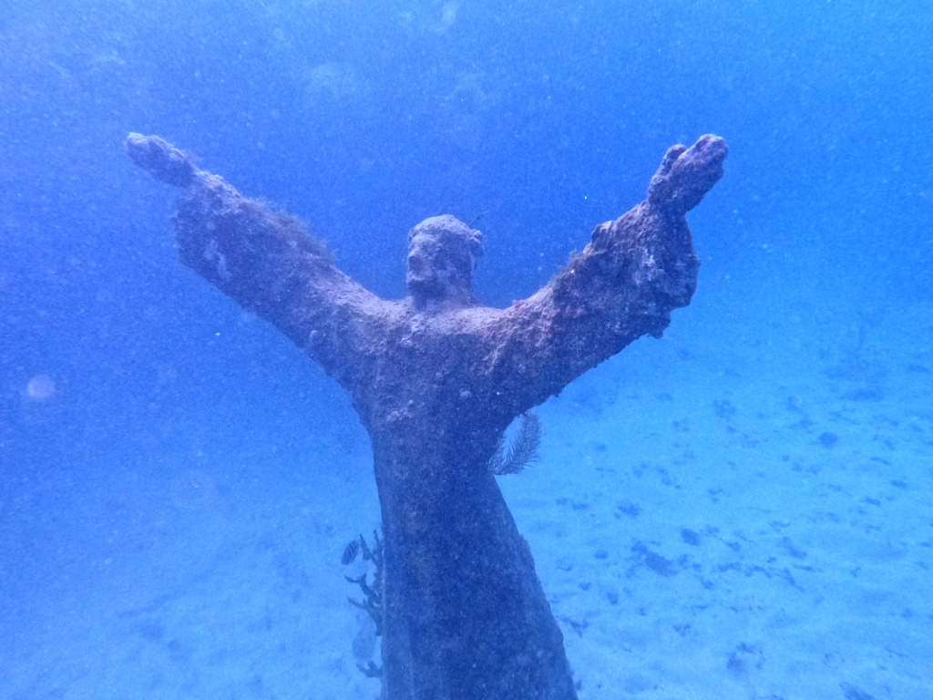 A statue of jesus christ with its arms raised in the air at the Grenada Underwater Sculpture Park