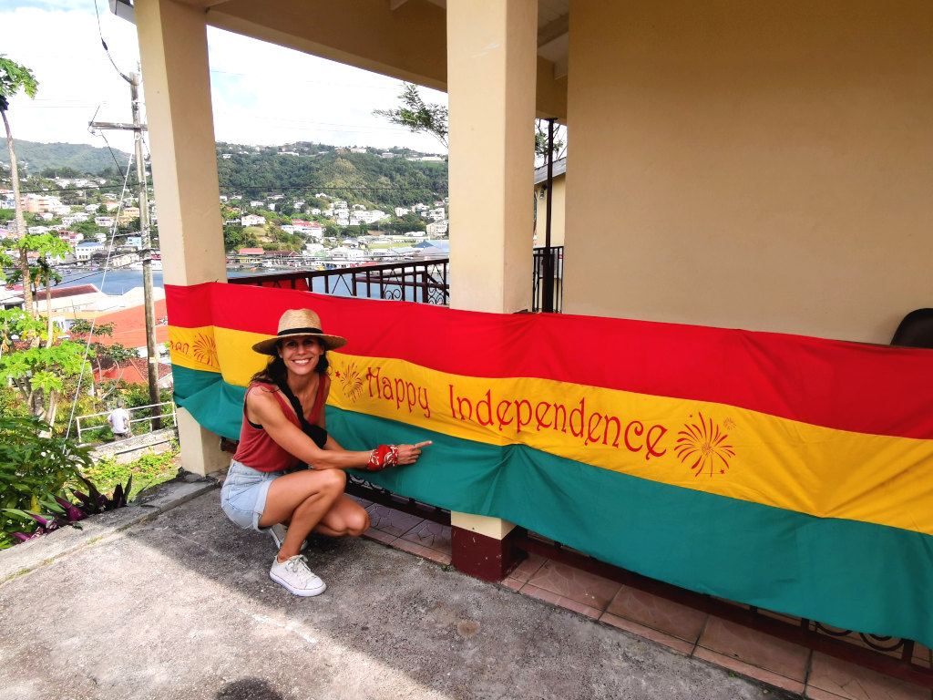 A woman crouched down in front of a red, yellow and green flag with Independence Day written on it