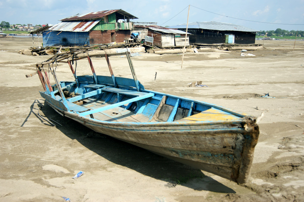 A boat and house boast sitting on the dry Amazon river bed near Leticia