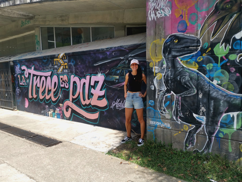 A woman in a pink hat standing in front of some graffiti art in Medellin