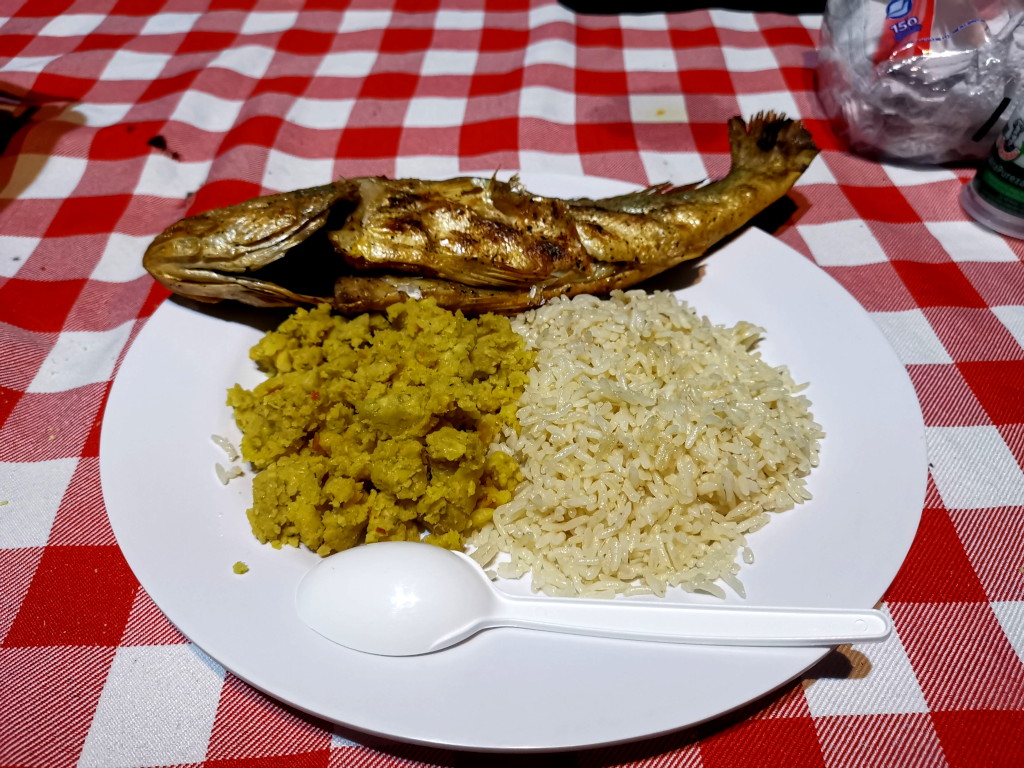 A grilled fish with rice and plaintain on a plate