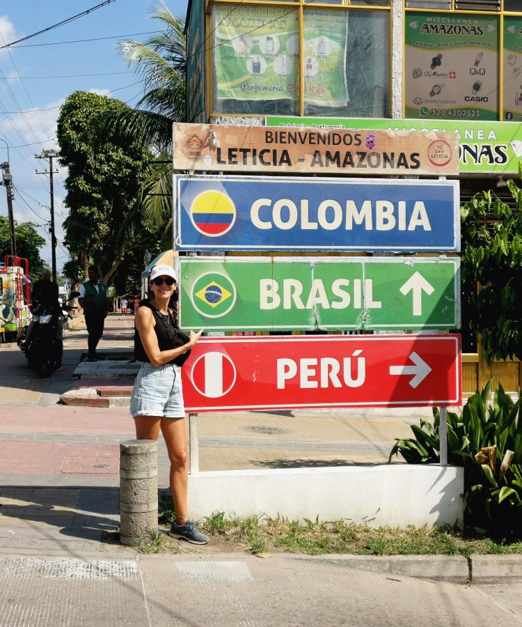 A woman standing in front of the Tres Fronteras Sign in Leticia Colombia