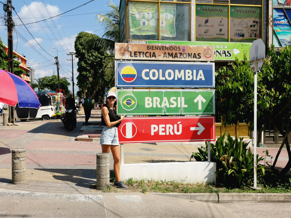 A woman standing in front of the Tres Fronteras Sign in Leticia Colombia