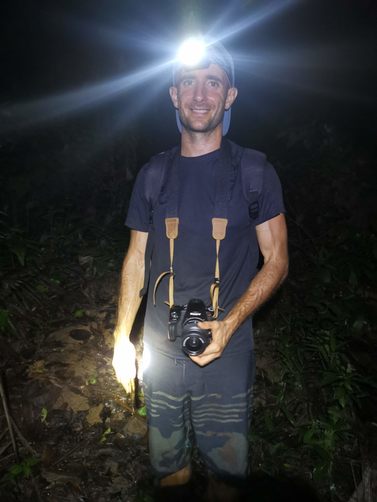 A man with a headlamp on while doing a nightwalk in the jungle