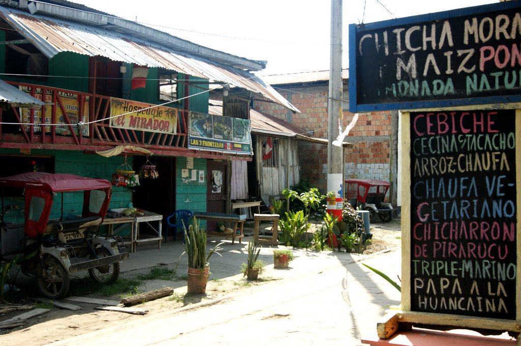 A quiet street with signs advertising food in Santa Rosa, Peru