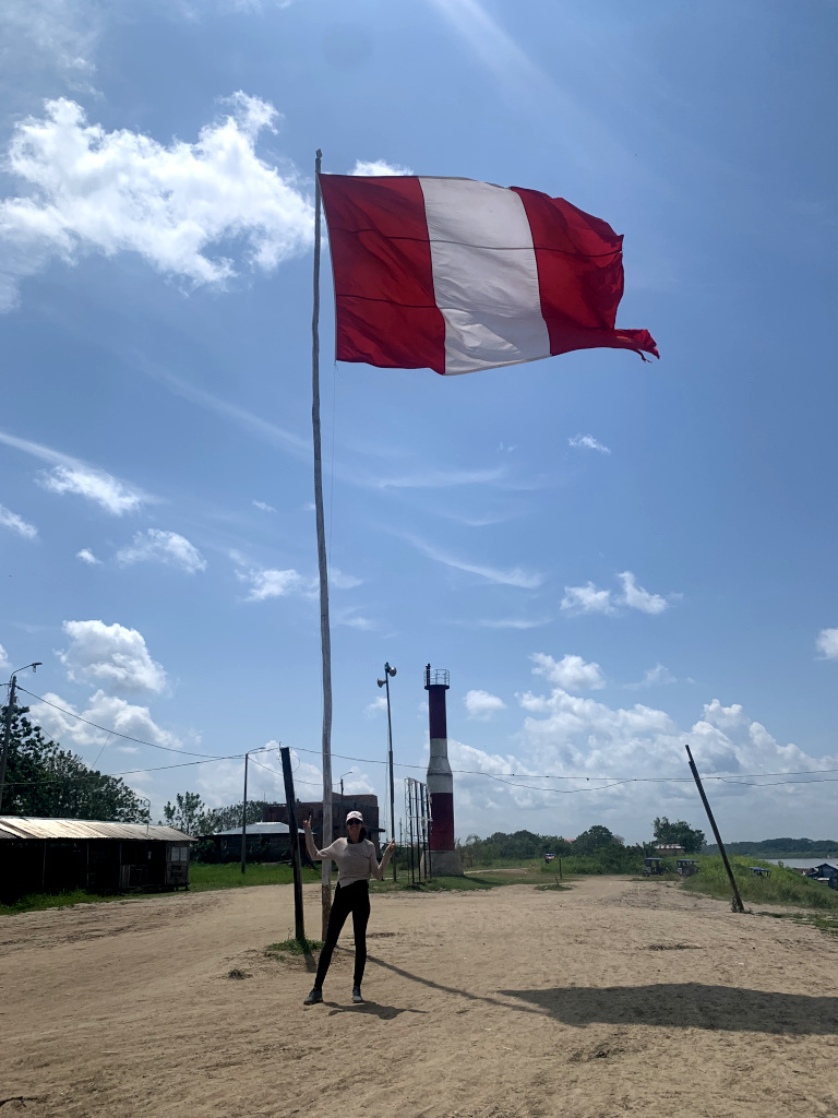 A woman standing next to a huge Peruvian flag