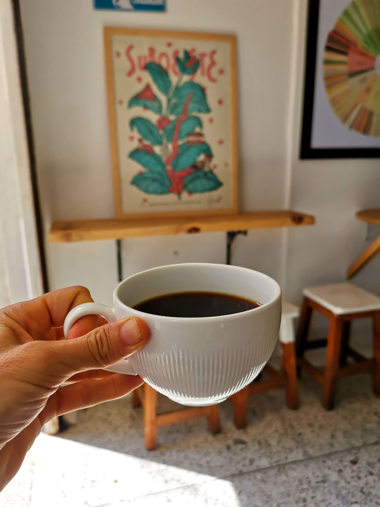 A hand holding a cup of coffee at Cielo Tostado Cafe in Laureles