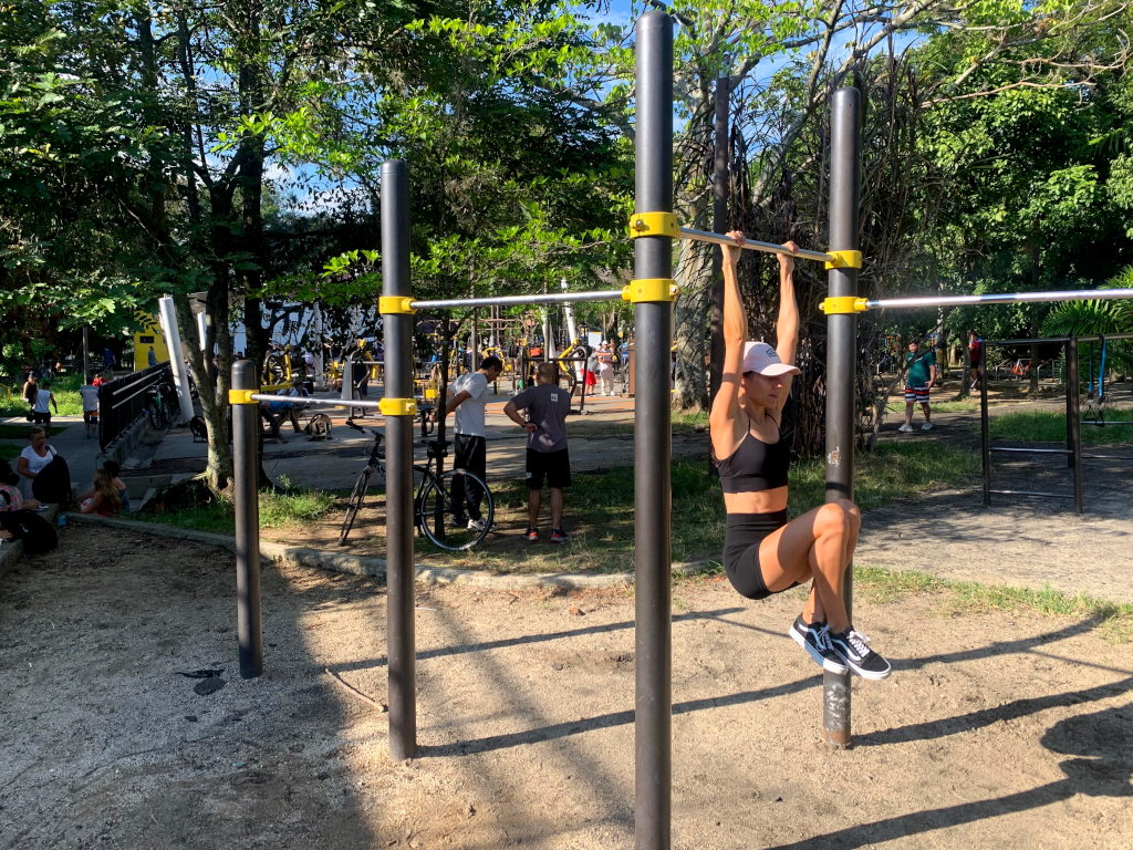 A woman hanging fromn a bar at a free outdoor gym medellin 