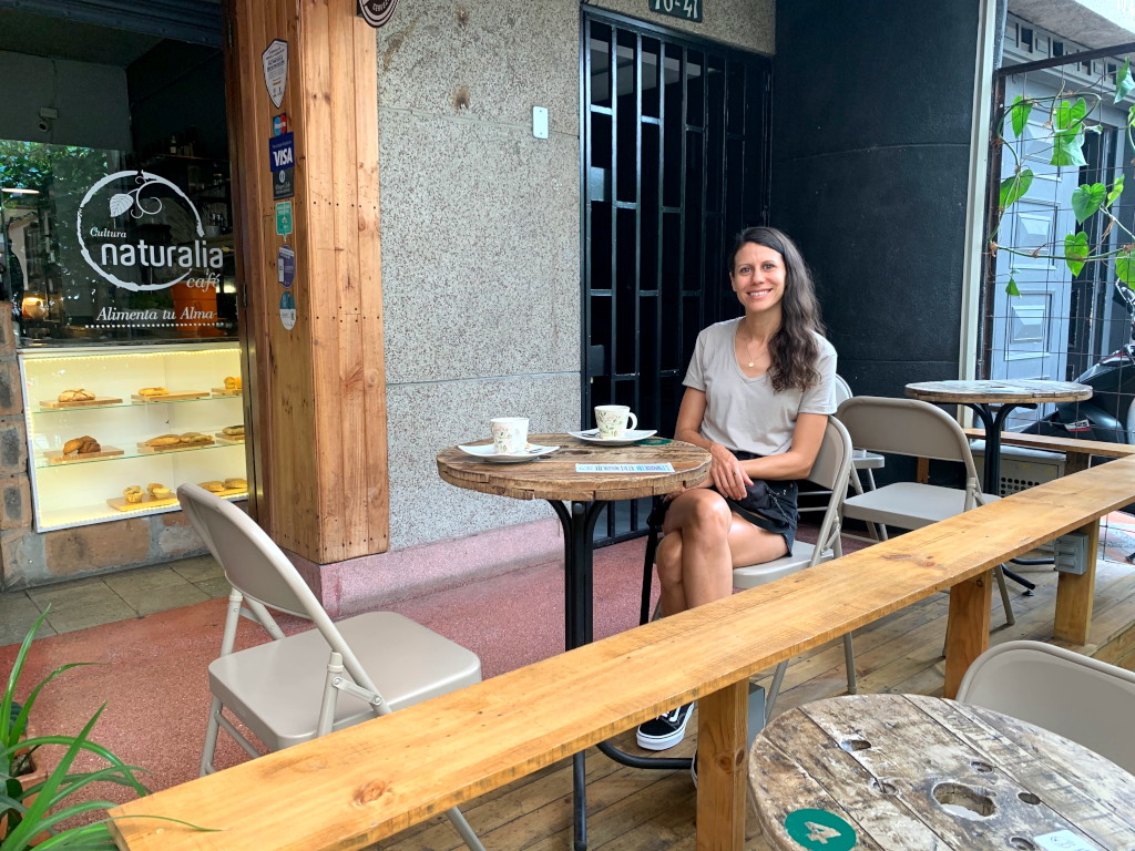 A woman sitting at a table outside of a cafe in Medellin 