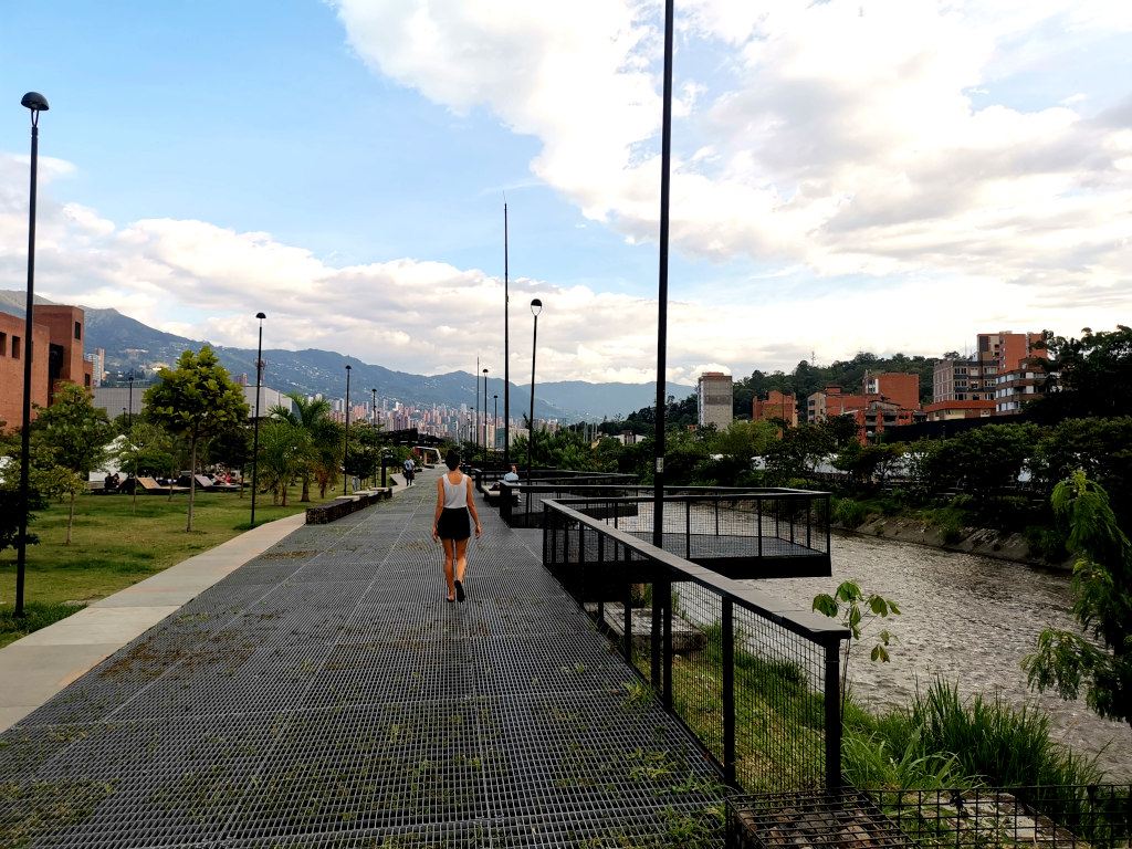 A woman walking along a metal walkway on the parque del rio in Laureles Medellin