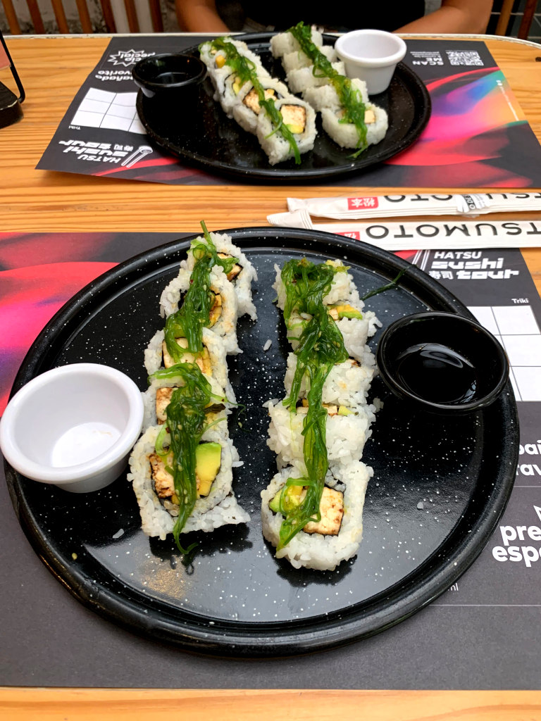 Two suhi rolls on a plate covered in light green seaweed
