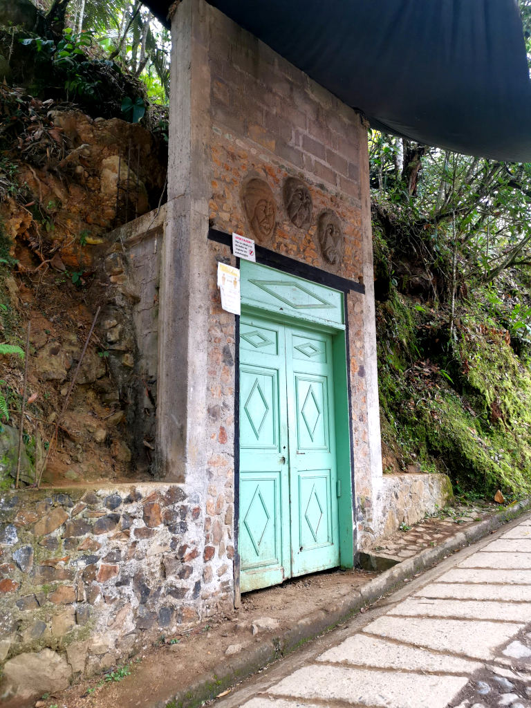 A green door in the side of a cliff that is the entrance to a bat cave in Jardin Colombia