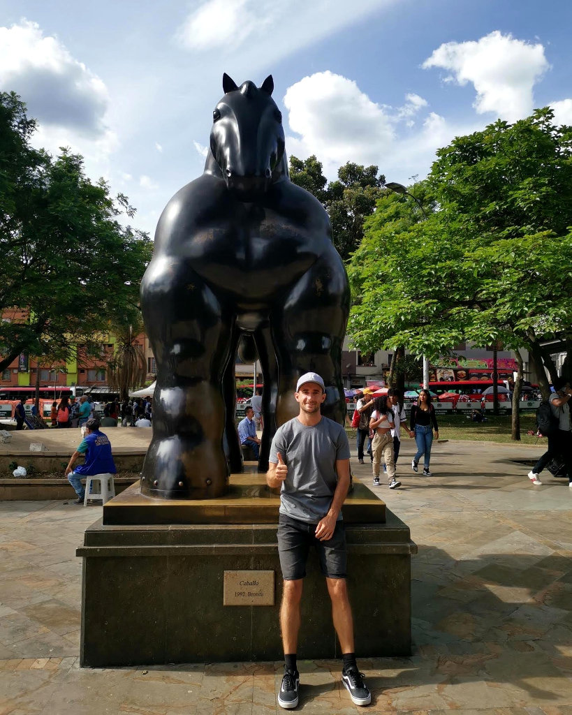 A man posing in front of a Botero statue 