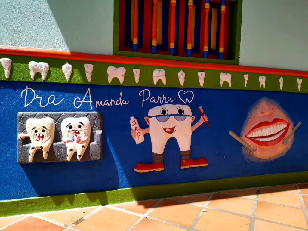 A zocolo on a wall in Guatape advertising a dentist with pictures of teeth 