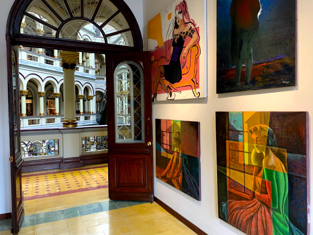 A room with colorful paintings on the walls and beautiful archways in the background at the Centro Commercial Palacio Nacional on of the best free things to do in Medellin
