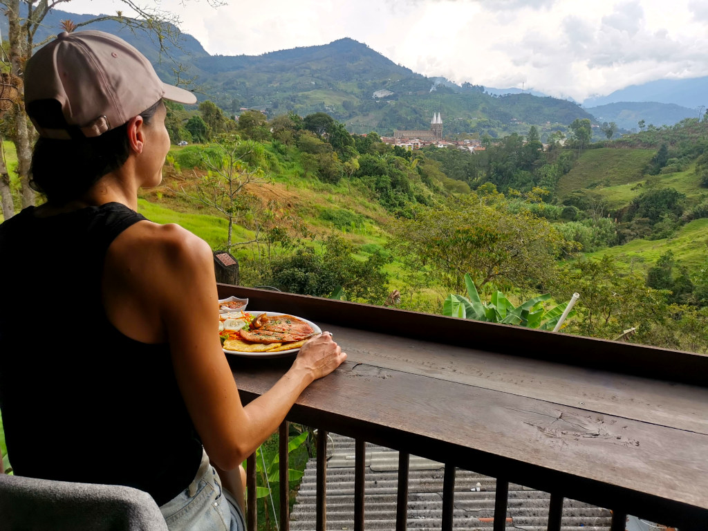 A woma sitting at a restaurant overlooking a town in the coffee region of Colombia