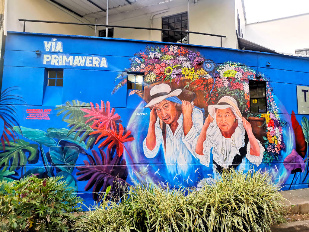 A painting of farmers carrying flowers on their back in Medellin