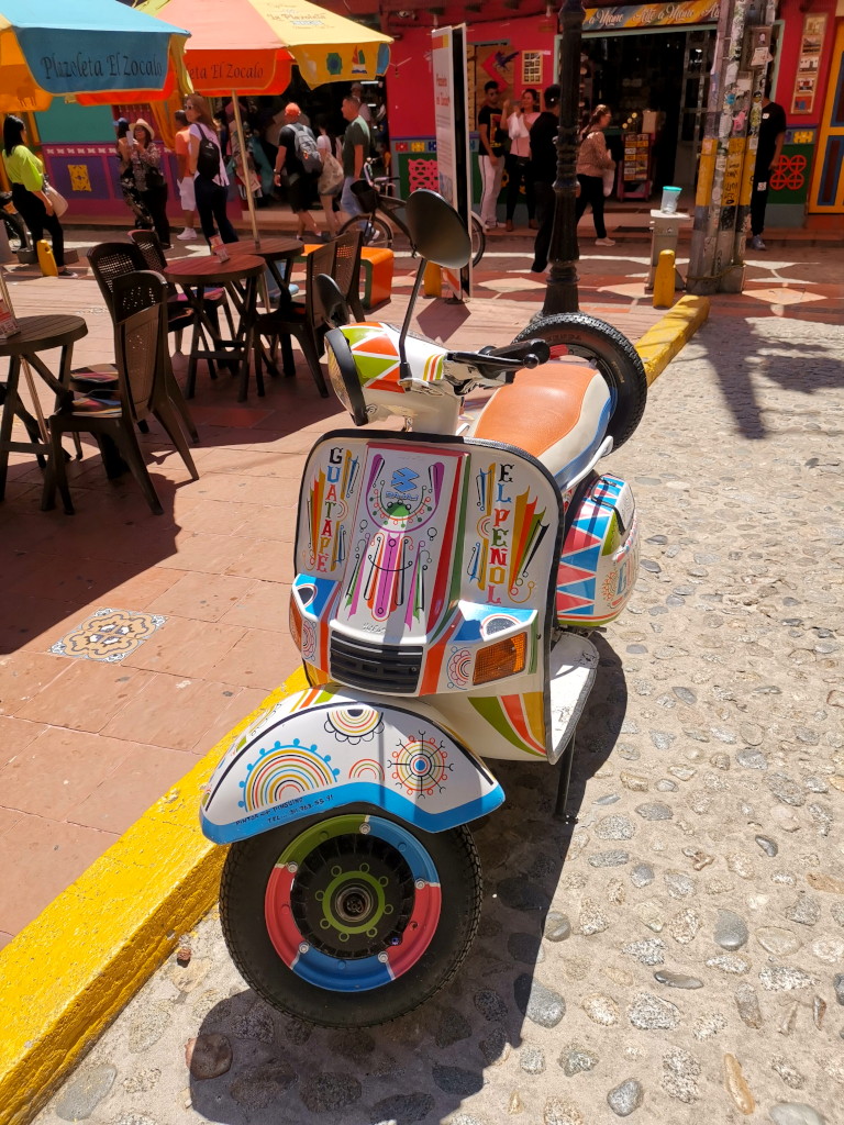 A colorful motorcycle parked on the main square of Guatape