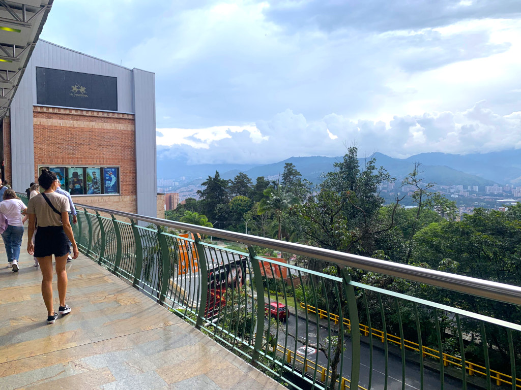 A woman walking on a terrase of El Tesoro Shopping Mall enjoying the view of the Medellin valley