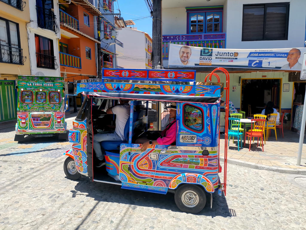 A colorful tuk tuk driving down the road one of the top things to do in Guatape