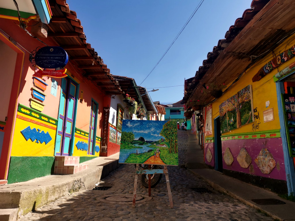 A colorful street in Guatapé with a painting 