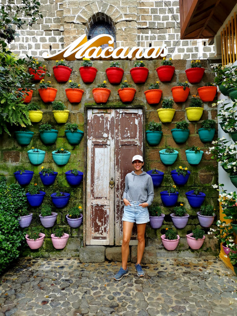 A woman standing in front of a wall with colorful plant pots