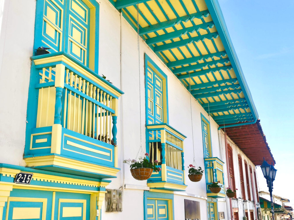 A colorful colonial building in colombia that is painted yellow and aqua blue