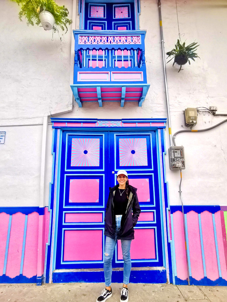 A woman standing in front of a colorful door on calle real in salento colombia