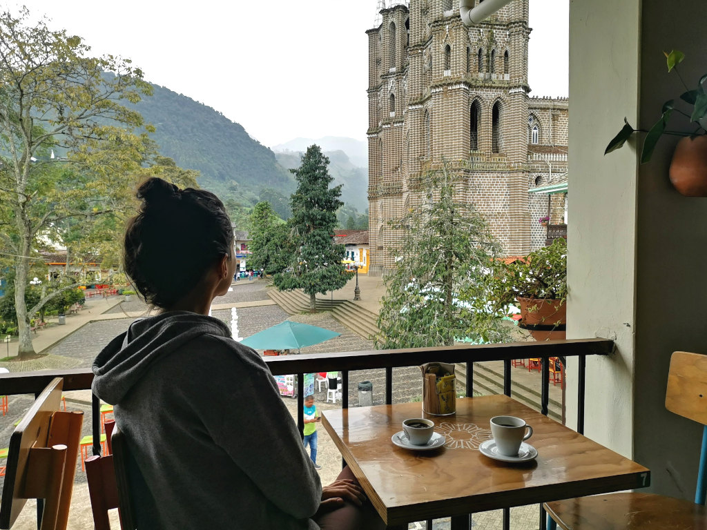 A woman sittin at table at a cafe overlooking the main square of Jardin Colombia