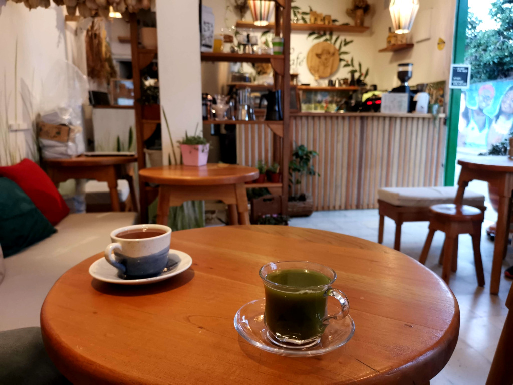 A table in a cafe with a glass of matcha and a glass of cup of hot chocolate on top of it