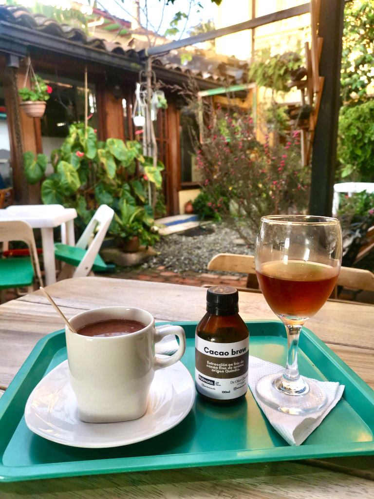 A table at a chocolate factory in Salento Colombia with a cup of hot chocolate and a wine glass full of cold brewed cocoa which is one of the best things to do in Salento