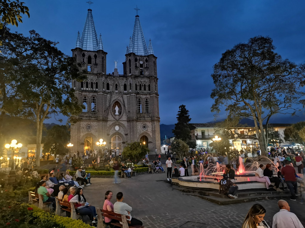 People relaxing in a town square in the evening which is one of the reasons to choose salento or jardin when visiting colombia