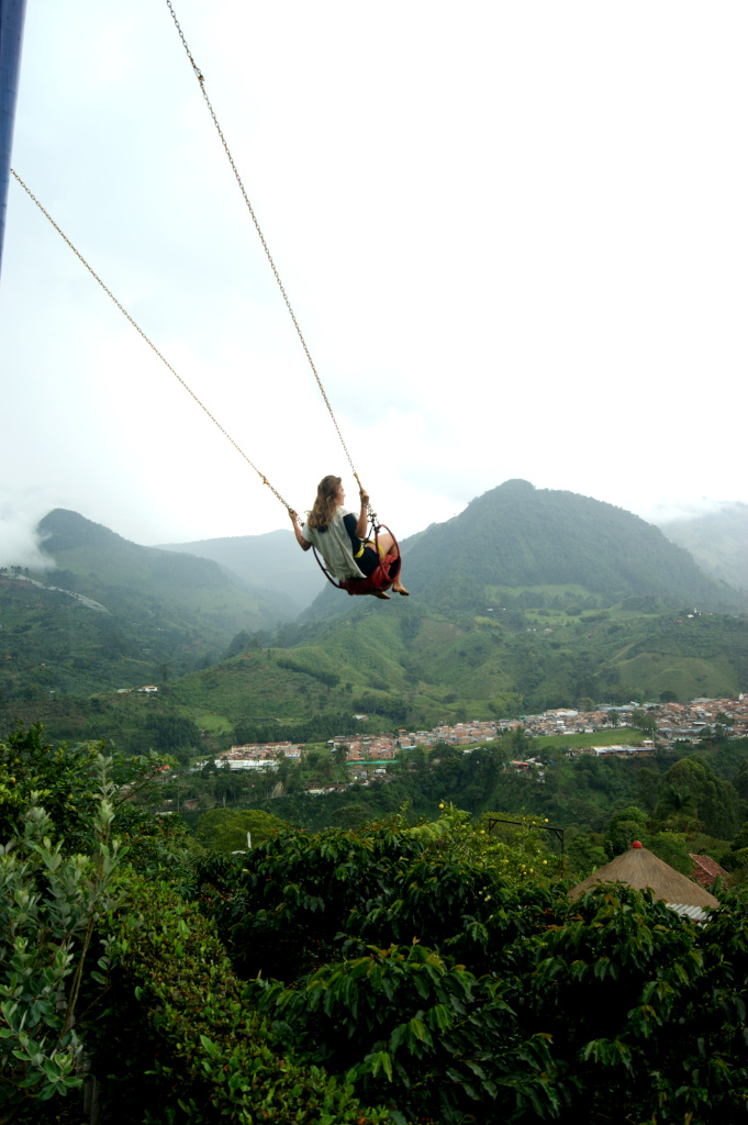 A woman on a swing in green hills